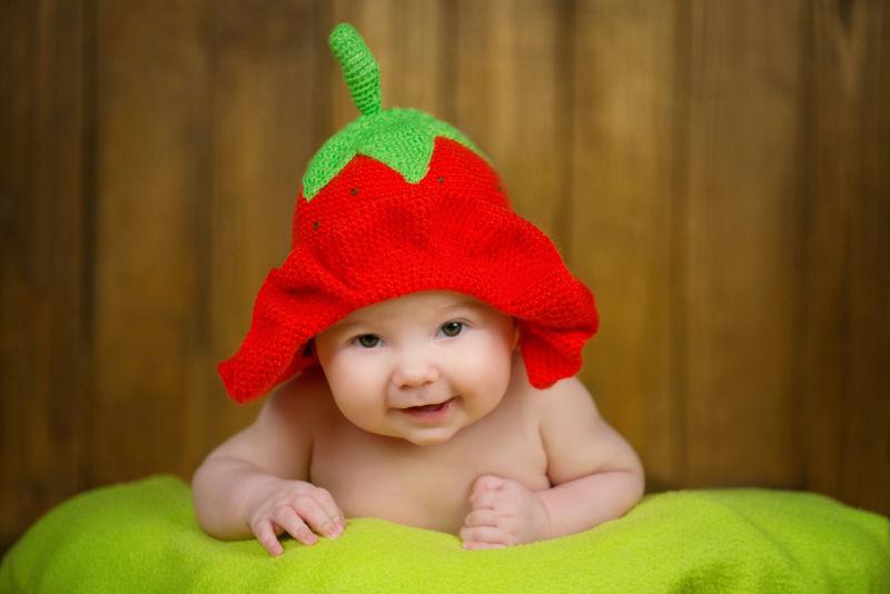 漂亮的小女孩戴着针织帽草莓