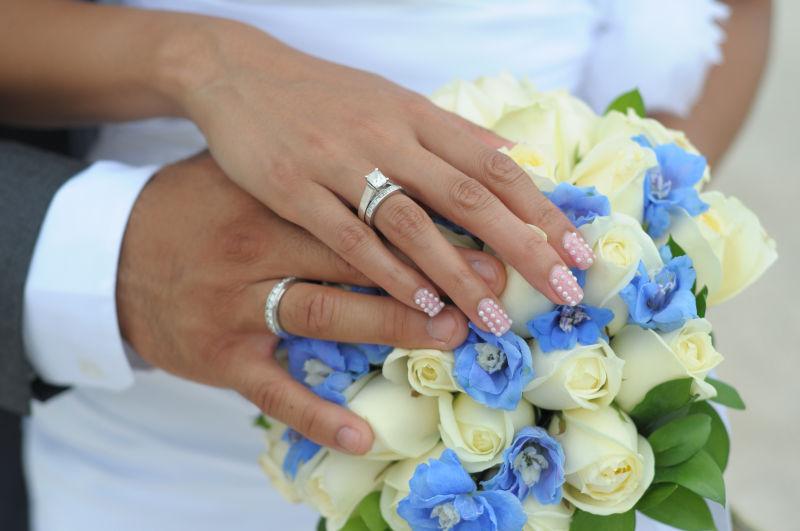 新娘和新郎在花束上炫耀他们的戒指