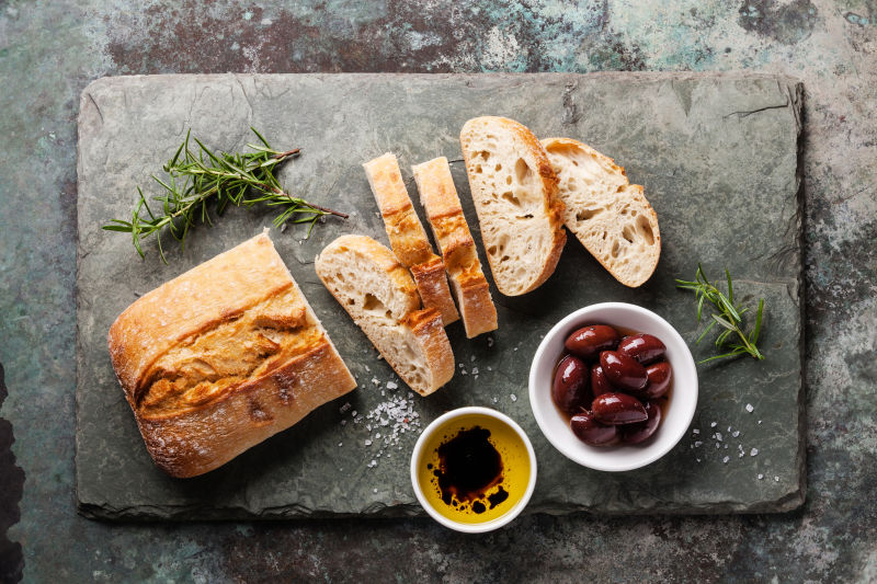石板背景橄榄油和面包