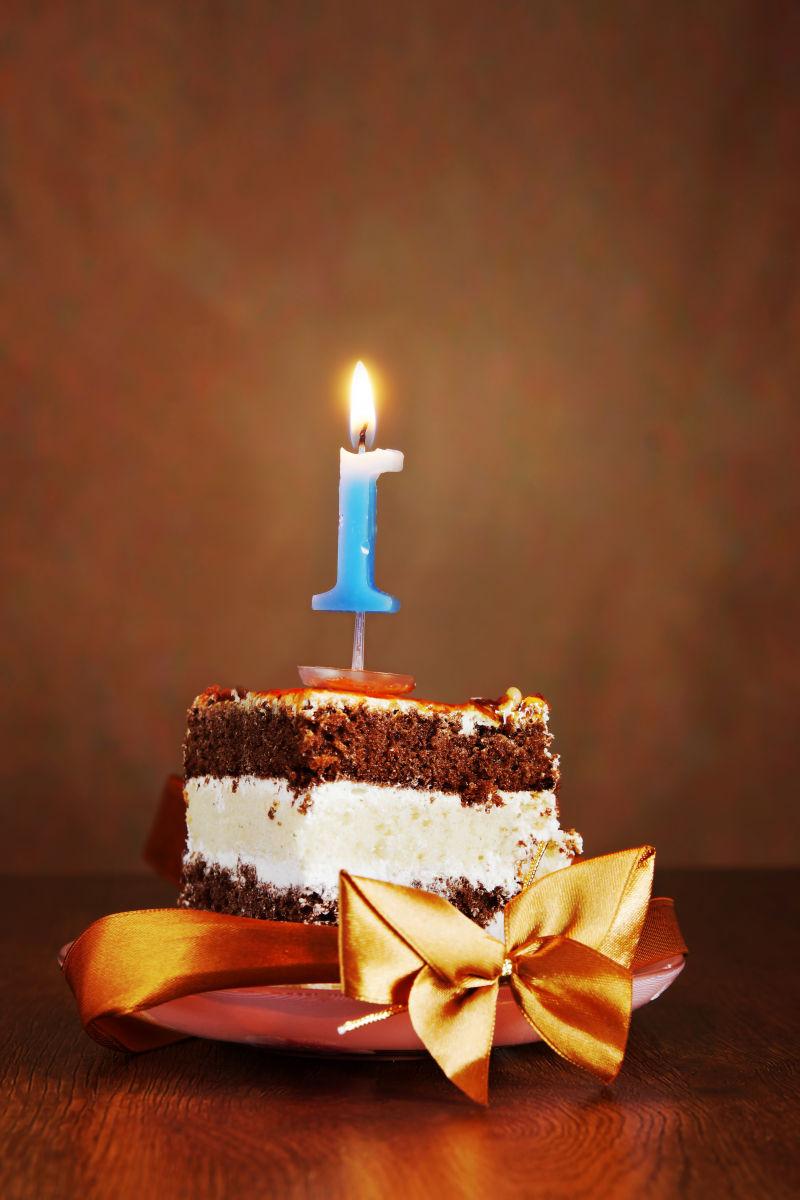一块生日巧克力蛋糕上蜡烛在木桌上
