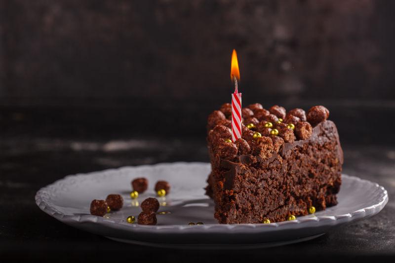 在黑暗的背景下用蜡烛制作巧克力蛋糕