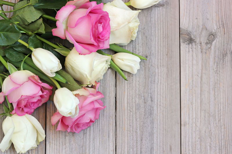 木制背景上的粉色玫瑰和白色郁金香