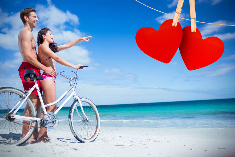 海滩穿着比基尼的情侣推着自行车