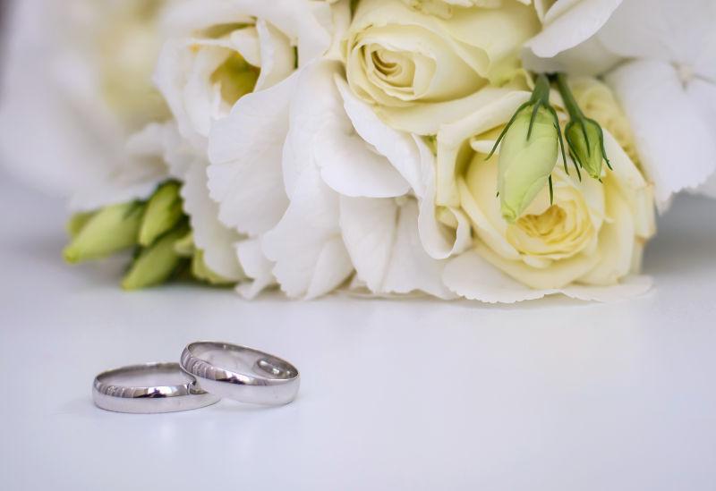 白色花卉前的结婚戒指