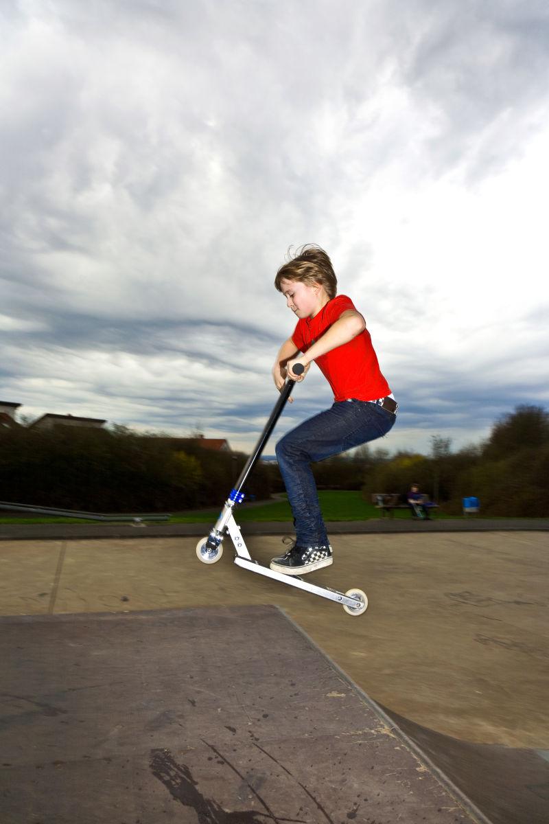 骑滑板车的男孩在滑板车上空降