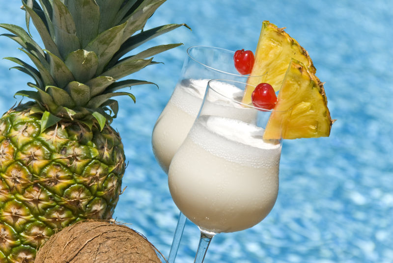 泳池旁的的菠萝和两杯椰子汁