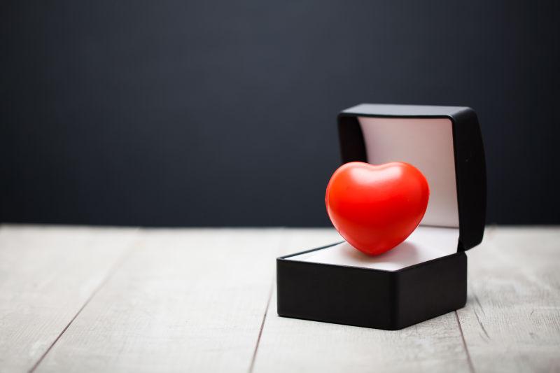 白色木桌上的黑色礼品盒和红色心