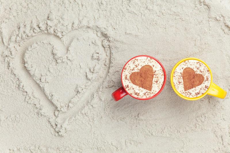 沙子上的爱心和两杯爱心咖啡