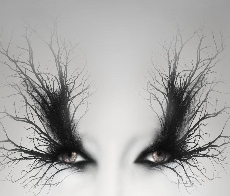 灰色背景下女性的两只眼睛和眼睛上的树枝创意