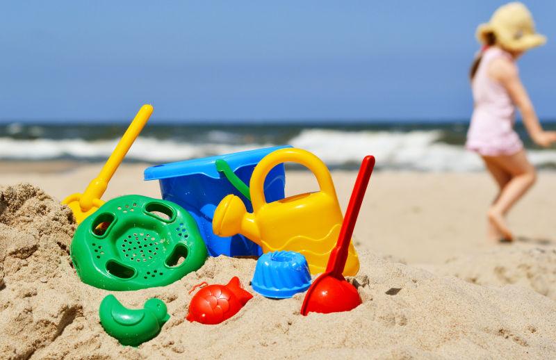 沙滩上的小女孩和沙水玩具