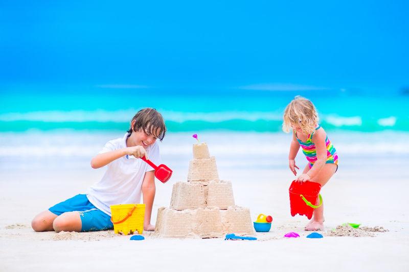 两个小孩在沙滩上堆城堡
