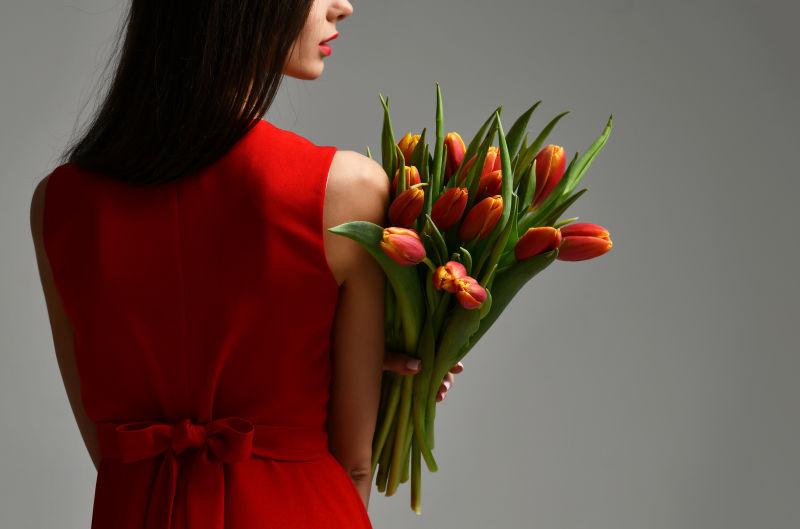 穿红色礼服的美女拿着郁金香花束