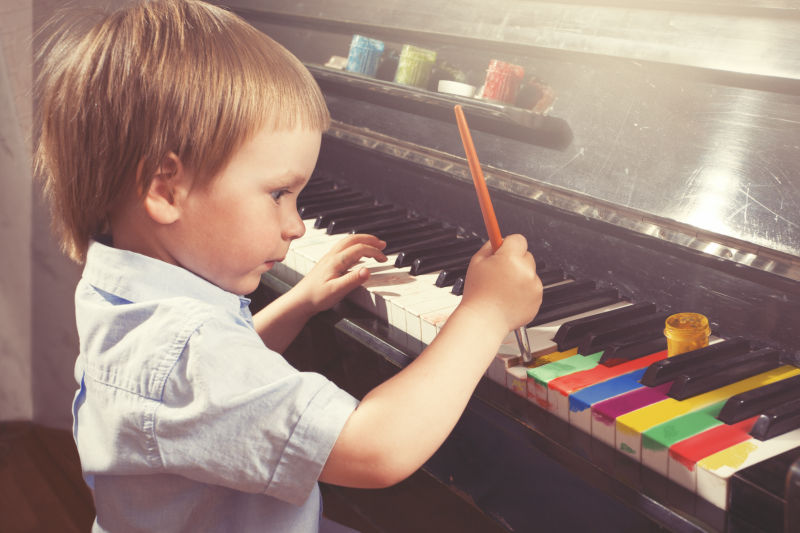在钢琴琴键上画画的小男孩