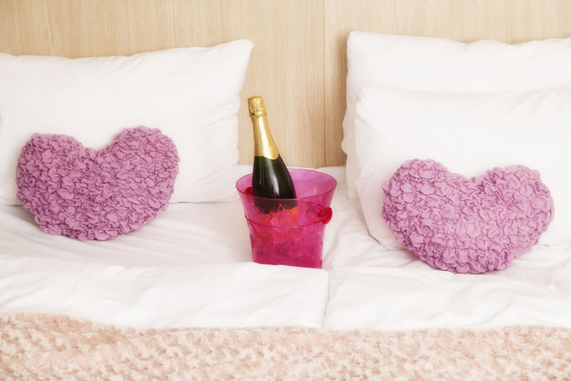 床上的心形抱枕和香槟酒