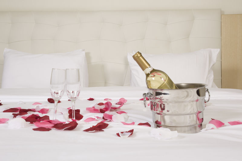 白色床上的香槟酒和玫瑰花瓣