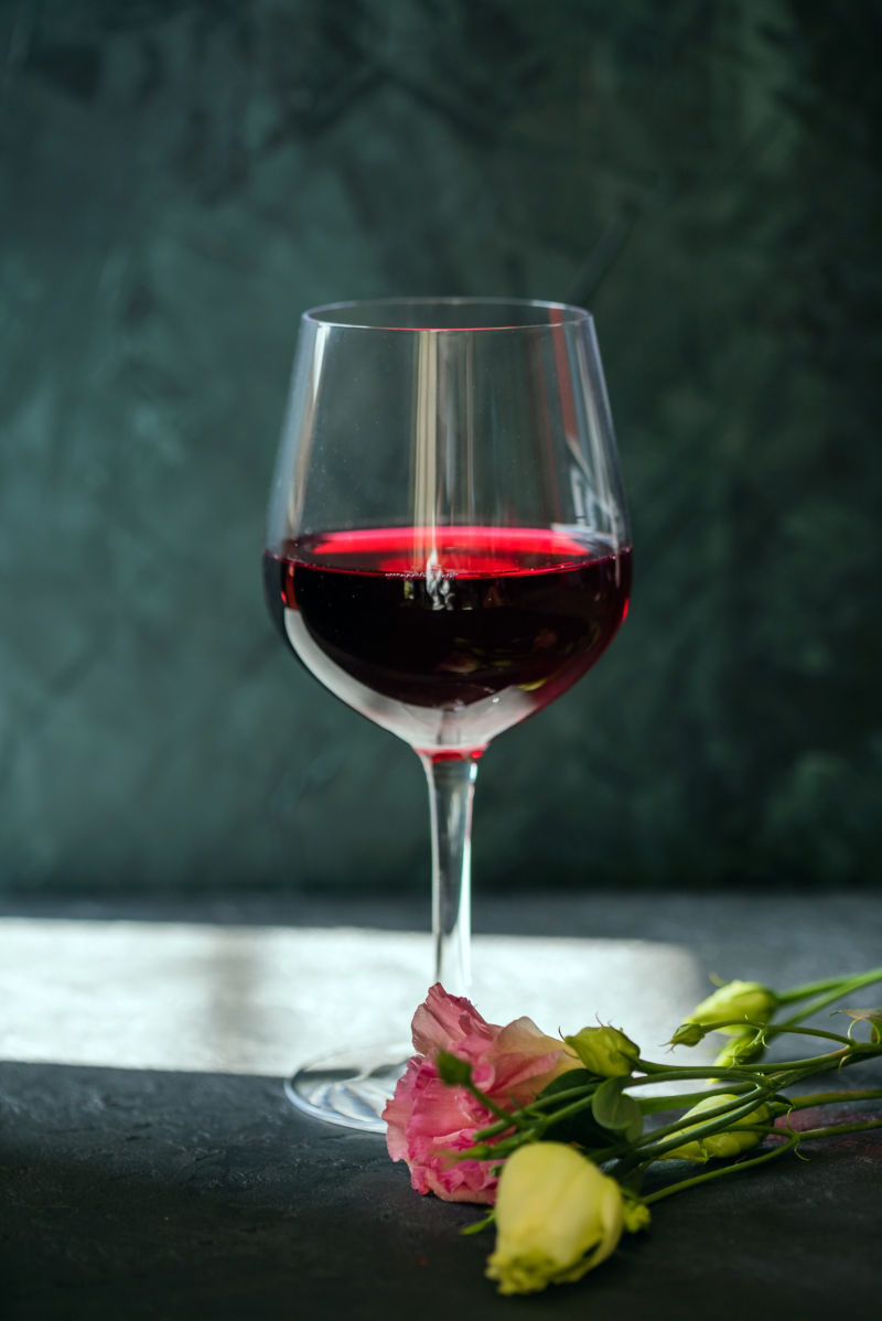 一杯红葡萄酒与玫瑰花朵