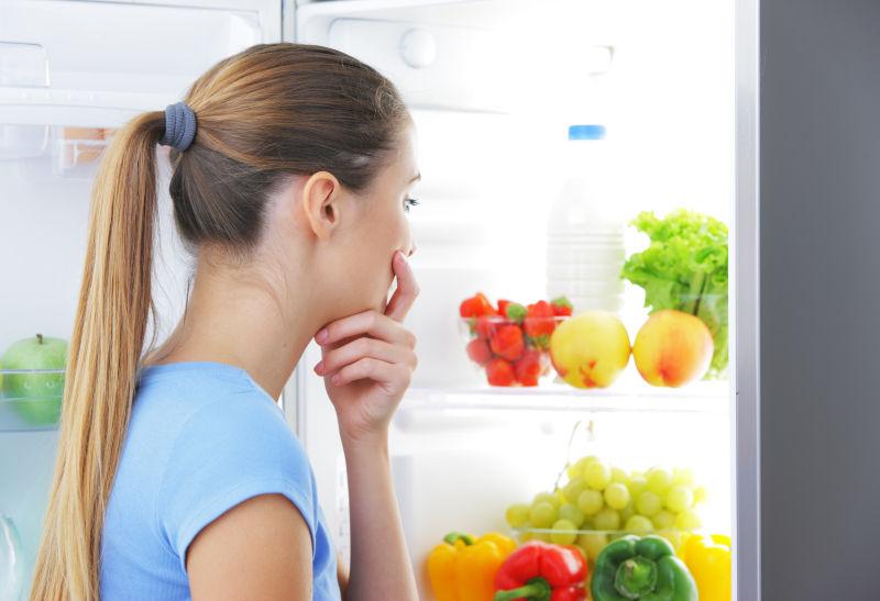 在冰箱里选择食物的年轻女性