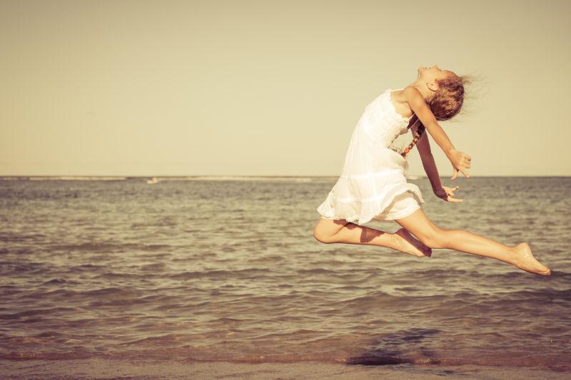 女孩白天在海滩上跳