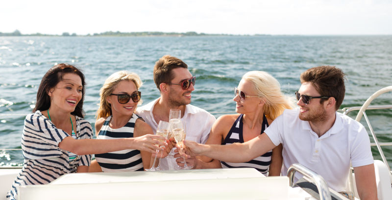 游艇上带着香槟微笑的朋友们举杯
