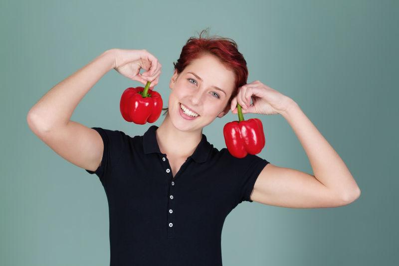 幸福的女人握着两个红柿子辣椒