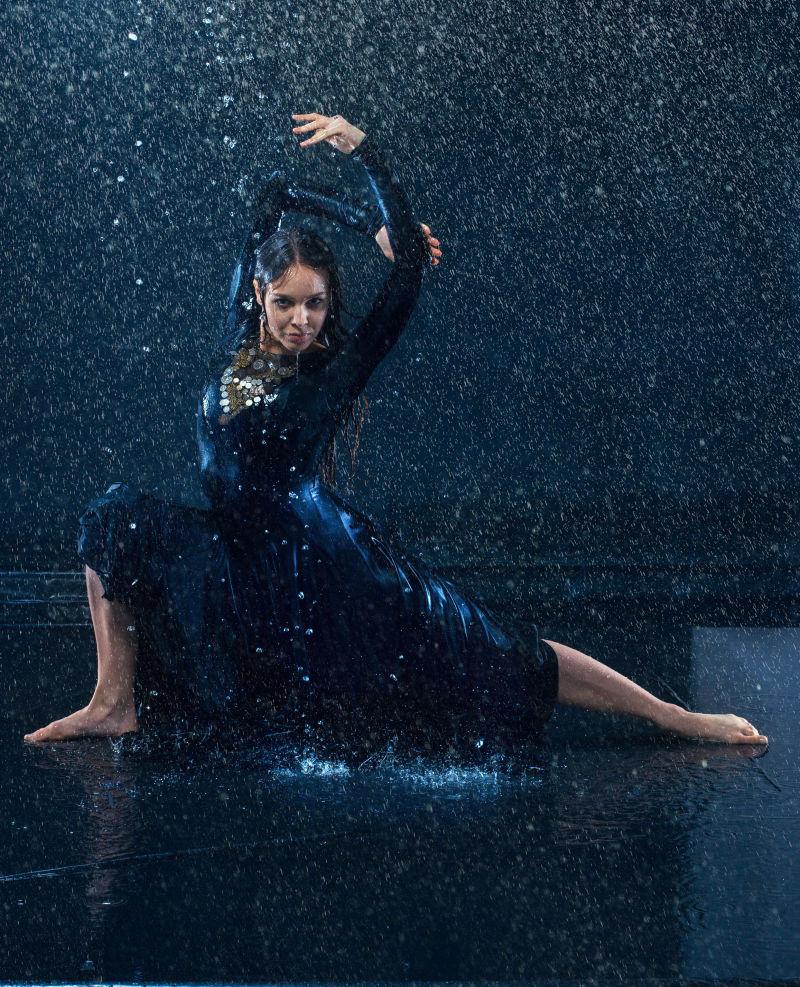 年轻美丽的现代舞蹈家穿着蓝色长裙水下长裙雨中跳舞
