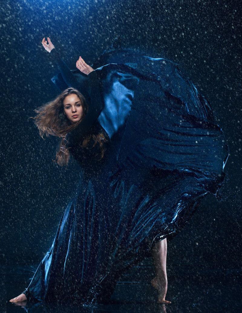 雨中起舞的穿着蓝色长裙的现代舞蹈家