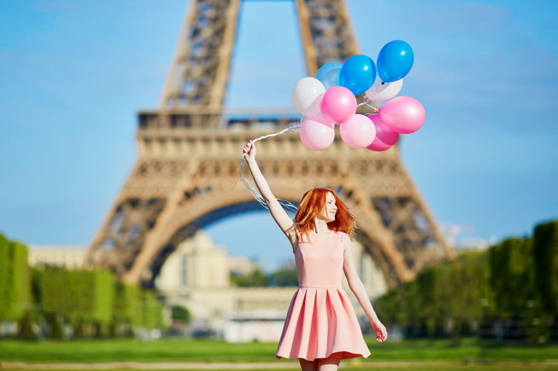 铁塔背景上的美女拿着多彩的气球