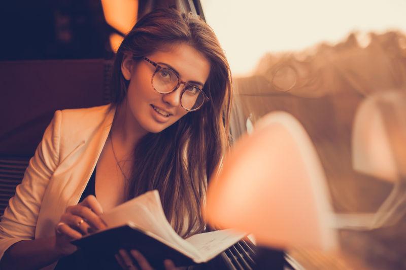 坐在火车上戴着眼镜看书的美女