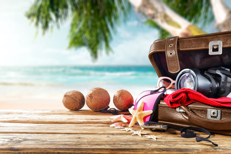 海滩背景下木板上的旅行手提箱