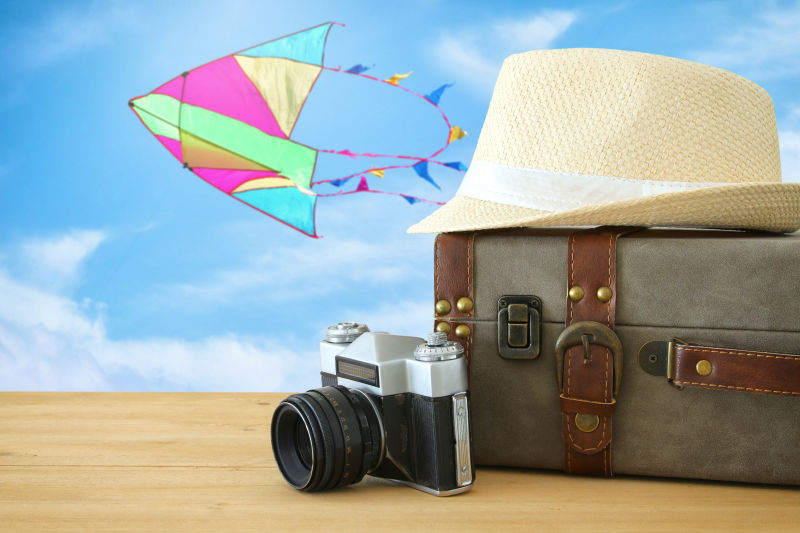 木桌上的旅行箱帽子和摄像机风筝旅游概念