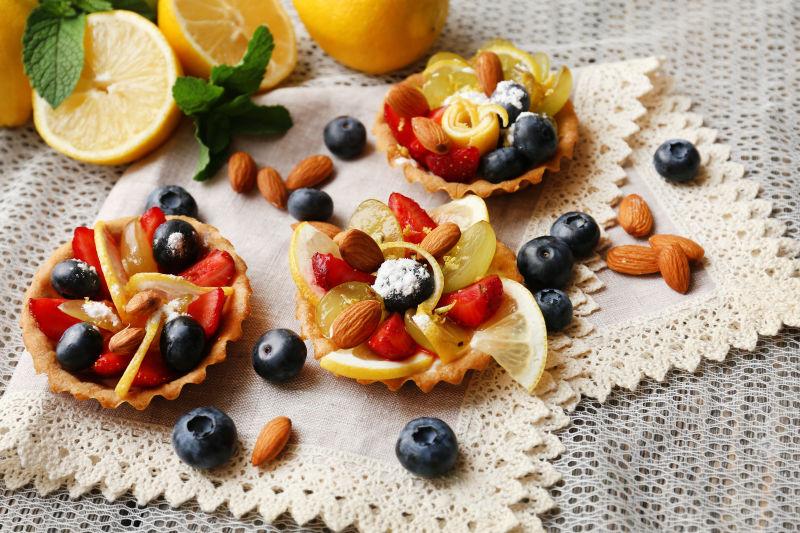 淡黄色餐布上的柠檬和草莓蓝莓浆果甜点