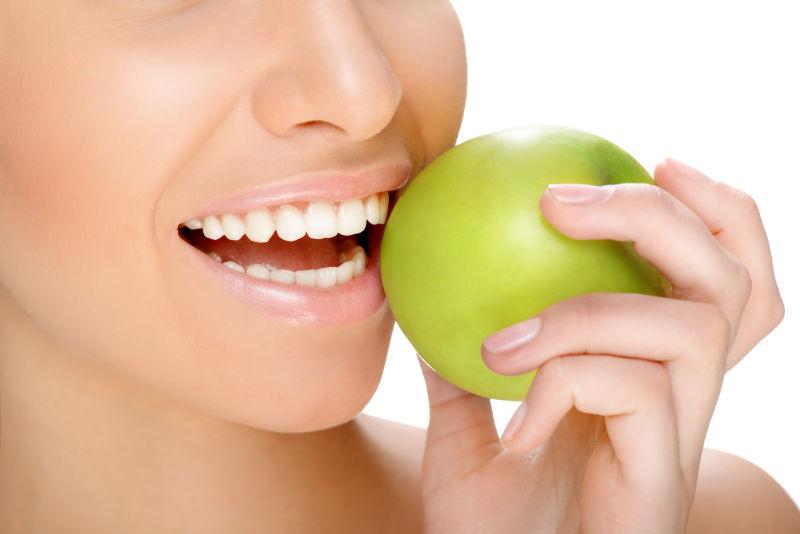 白色背景下拿着绿色苹果露着牙齿的人