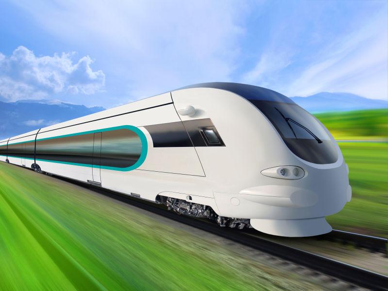 蓝天白云下绿色草地上的铁轨上高速行驶的超流线型列车