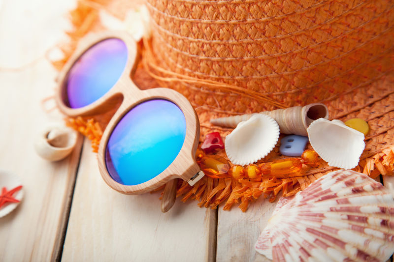 木桌上的太阳眼镜和草帽旅游物品