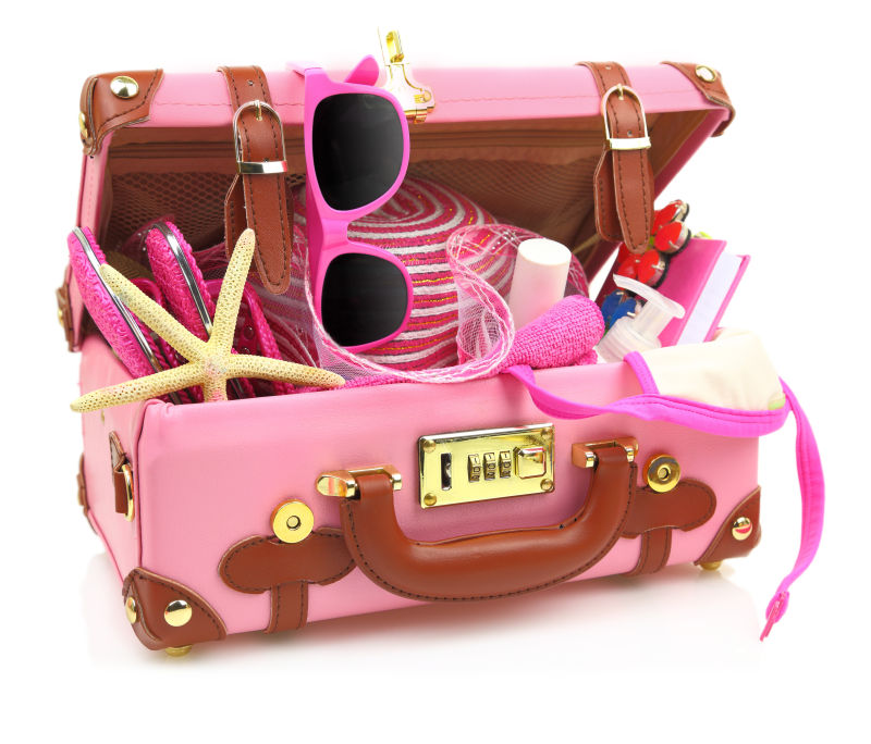 准备旅行的粉红色手提箱与夏季设备隔离