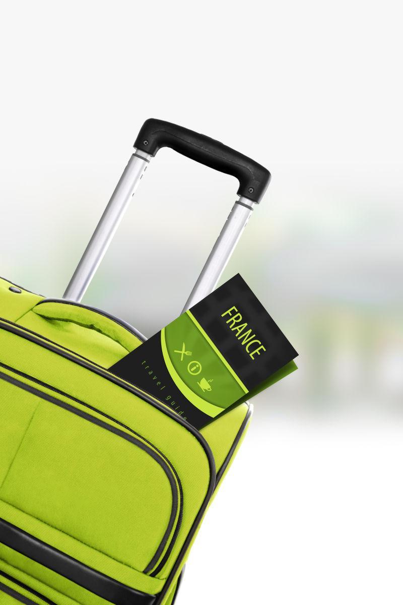 带旅行指南的绿色手提箱