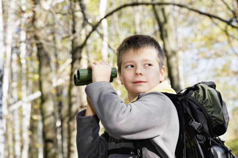 树林中拿着双筒望远镜的男孩