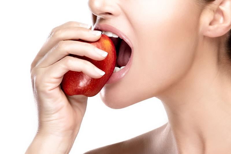 白色背景前吃苹果的女人