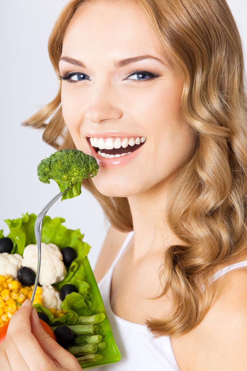 年轻金发美女吃绿色蔬菜
