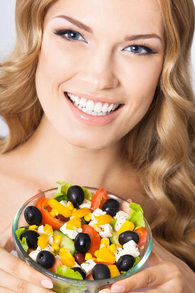 年轻美女微笑的端着健康蔬菜沙拉