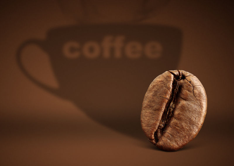 棕色咖啡杯背景前的一粒咖啡豆