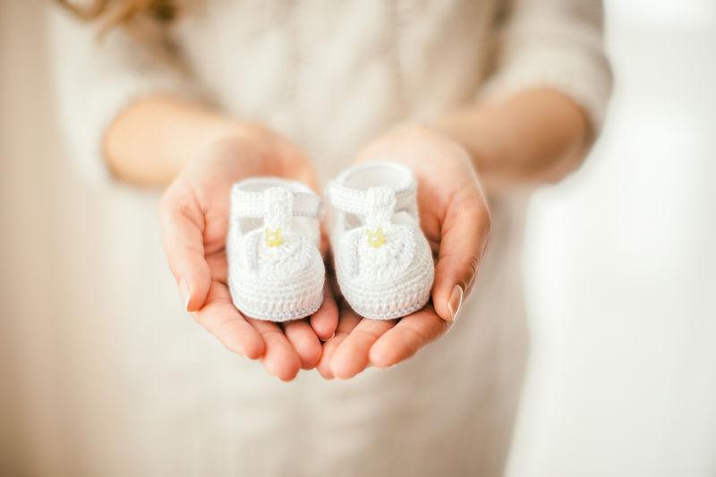 一位怀孕的孕妇双手托着一双小鞋子