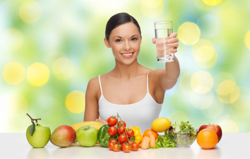 快乐的女人带着水玻璃的健康食品