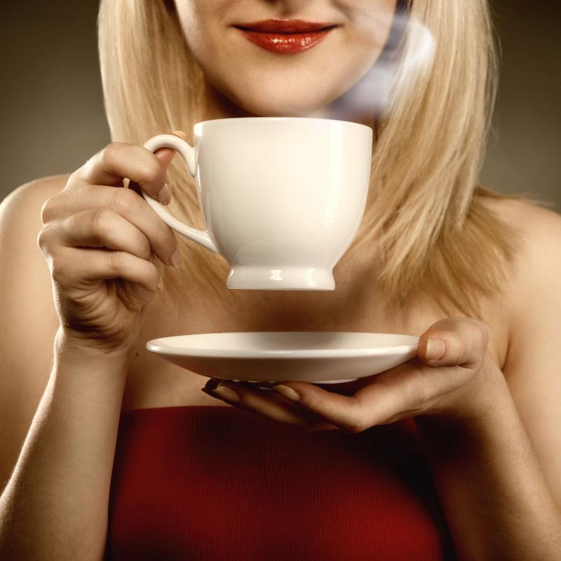 托着盘子拿着杯子喝咖啡的女人
