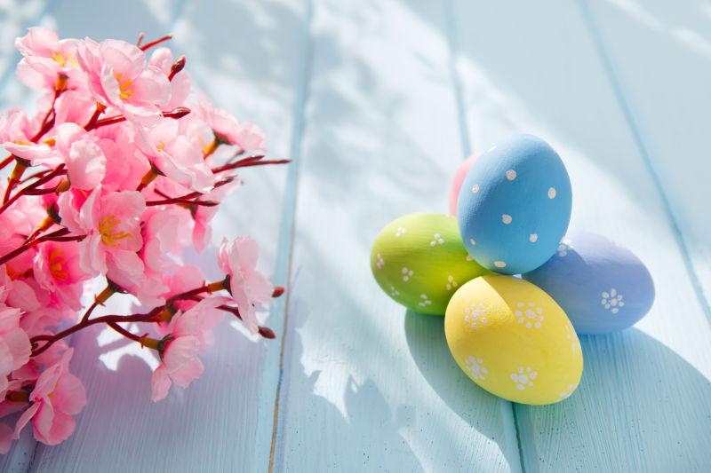 阳光下木桌上的复活节彩蛋和粉色花朵