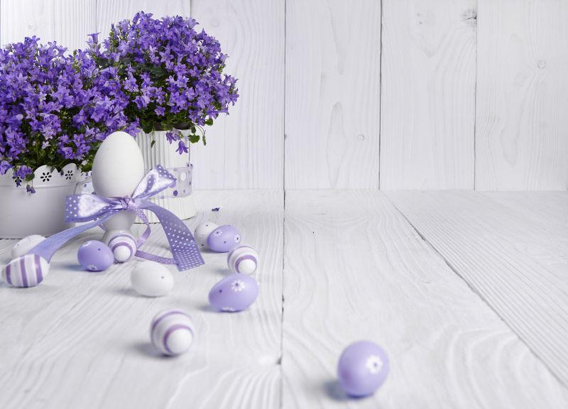 白色木制背景下的复活节彩蛋和紫色花朵
