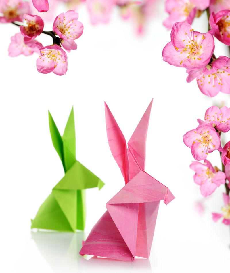 白色背景上粉色桃花下的复活节兔子折纸