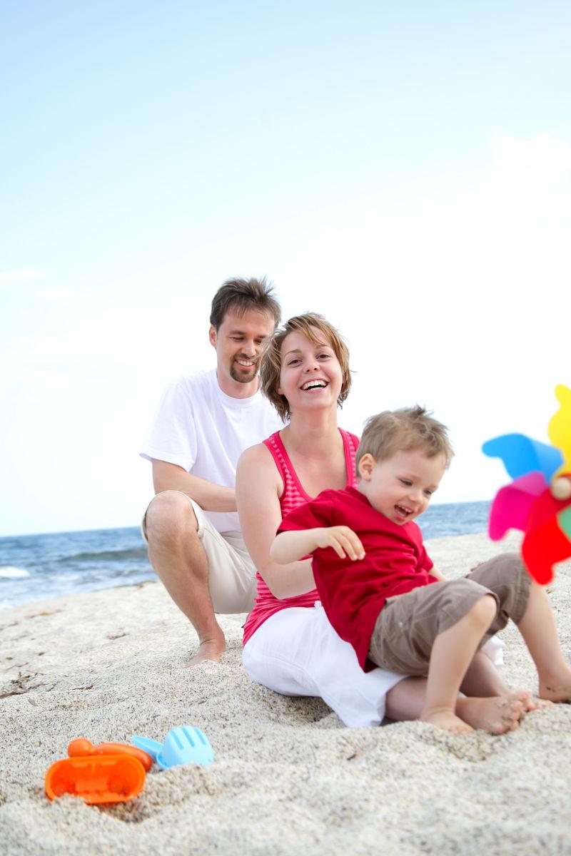 坐在海滩上玩耍的幸福的一家人