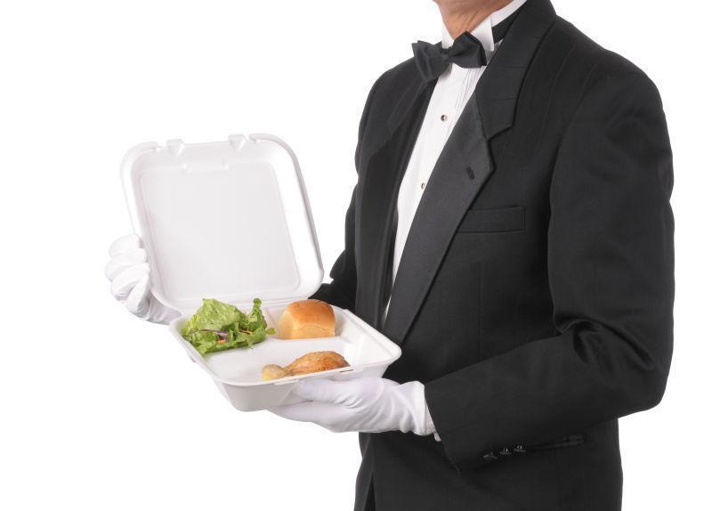 服务员拿着一个盛着一个面包和鸡腿的饭盒