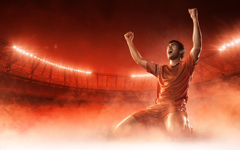 足球场上庆祝红色烟雾背景下的足球运动员